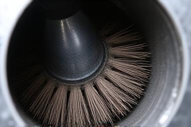 Close-up of a rotary brush head cleaning inside a metal duct